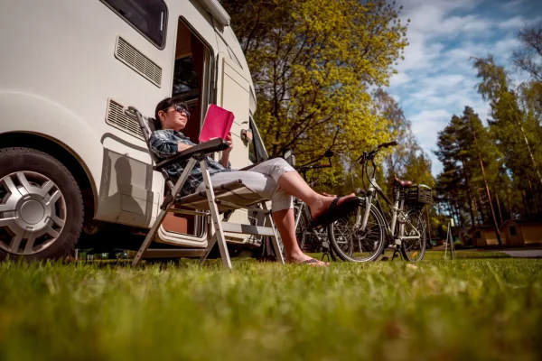 Personne assise en train de lire devant son camping car